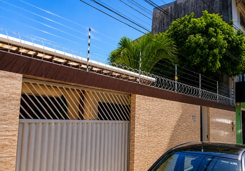 Instalação de cerca elétrica com concertina realizada pela Força e Luz no bairro Alecrim, em Natal RN, com arame inox, hastes de alumínio de 6 isoladores, central de choque de 18 mil volts, bateria Moura, sirene, aterramento e placas de advertência.