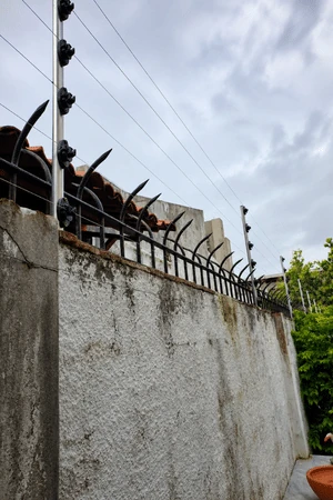 Instalação de cerca elétrica realizada pela Força e Luz no bairro Petrópolis, em Natal/RN, utilizando arame inox, hastes de alumínio com 6 isoladores, central de choque de 18 mil volts, bateria Moura, sirene, haste de aterramento e placas de advertência.
